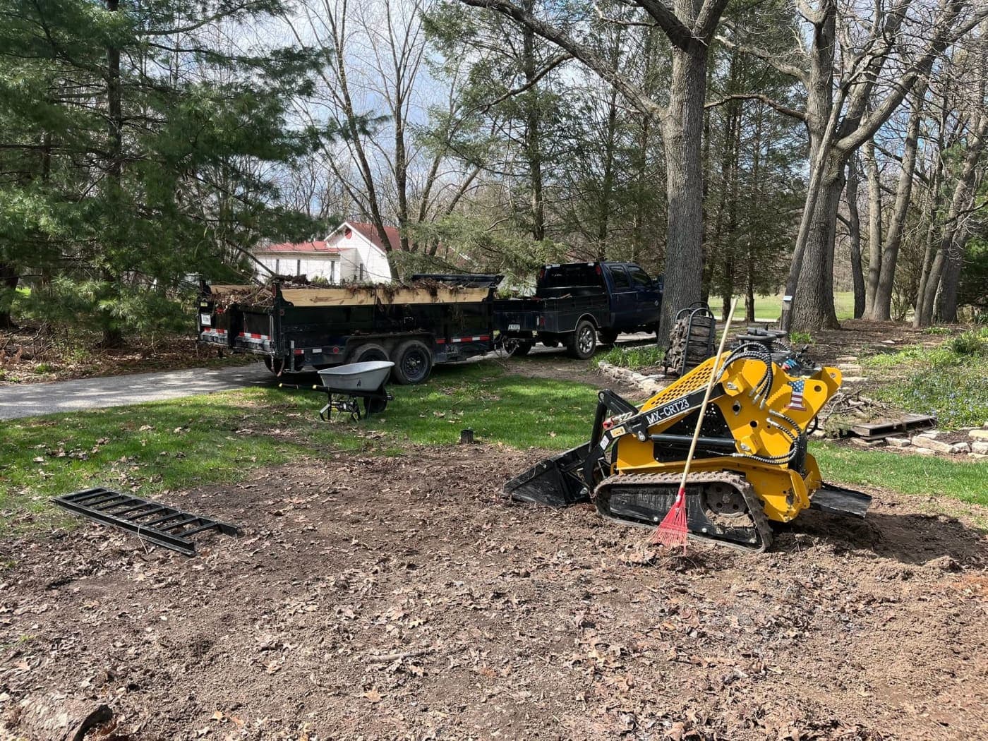 Compact track loader and dump trailer working a yard cleanup